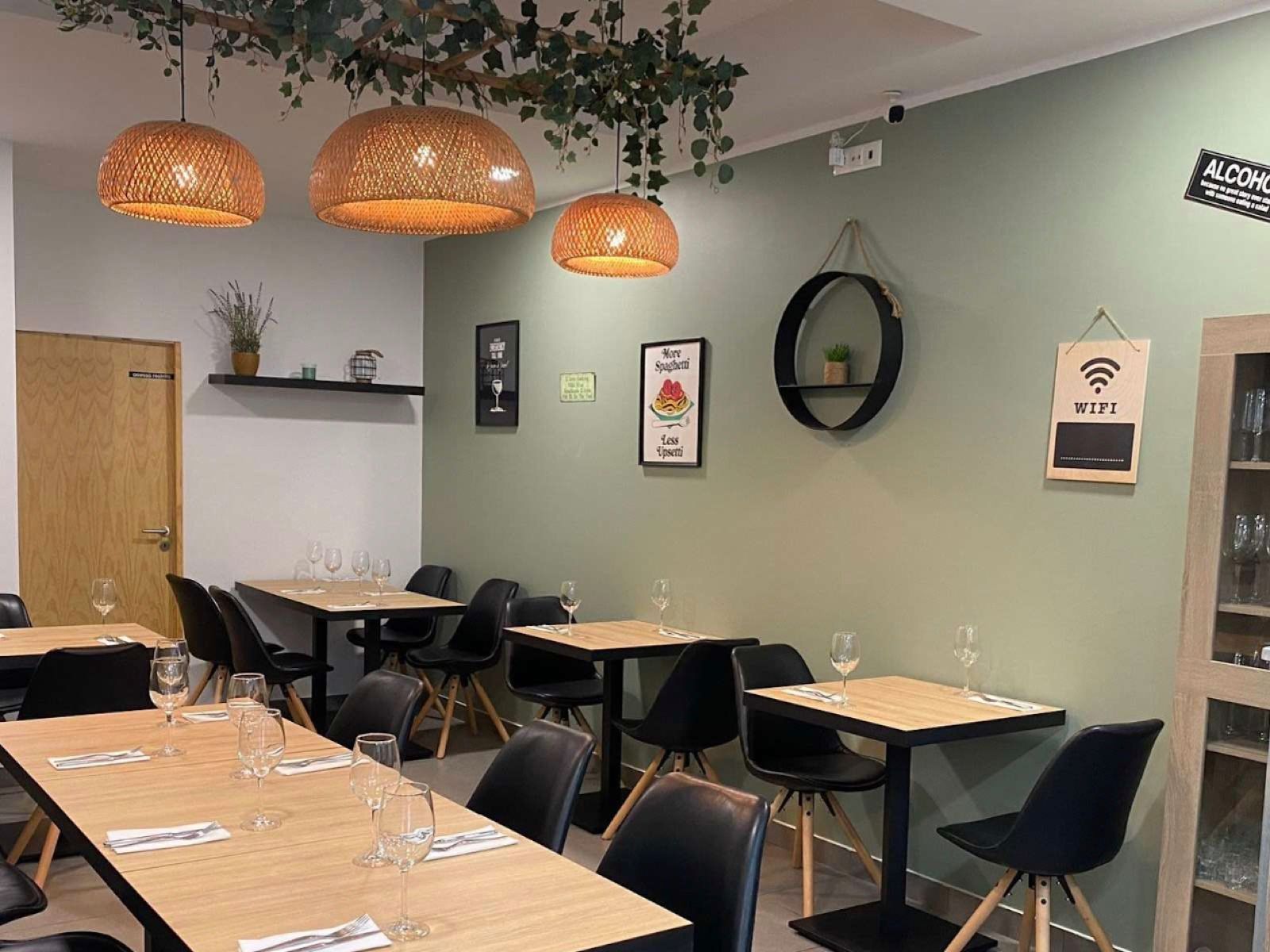 Sala do restaurante, com paredes verdes e candeeiros de vime